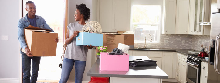 Happy couple moving into a home and carrying boxes.
