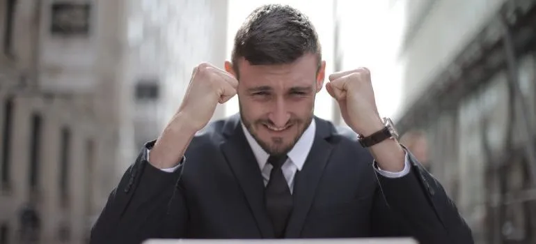 Man in black suit with laptop, happy