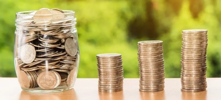 A jar and three stacks of coins to pay for movers Everett WA.