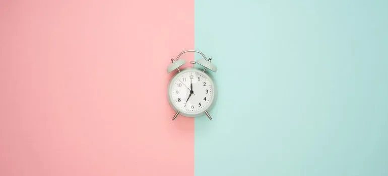An alarm clock on a pink and blue surface. 