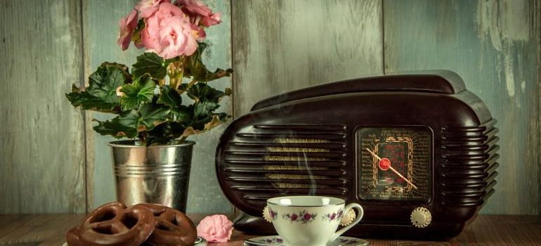 Vintage radio and pot of flowers behind a cup of coffee and plate of cookies