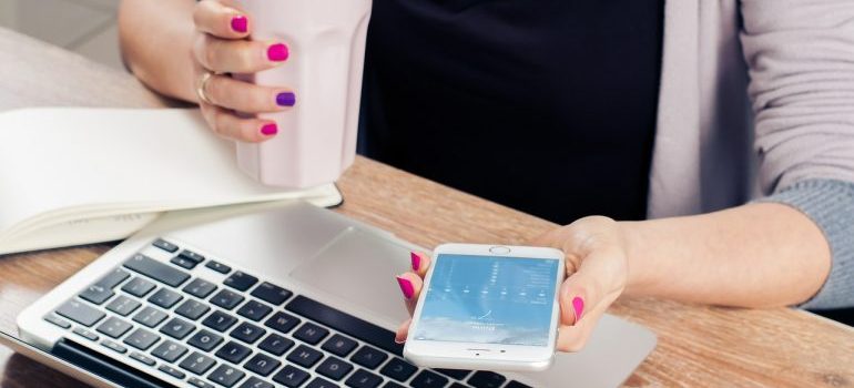 A woman researching moving companies Marysville WA on a phone and laptop. 