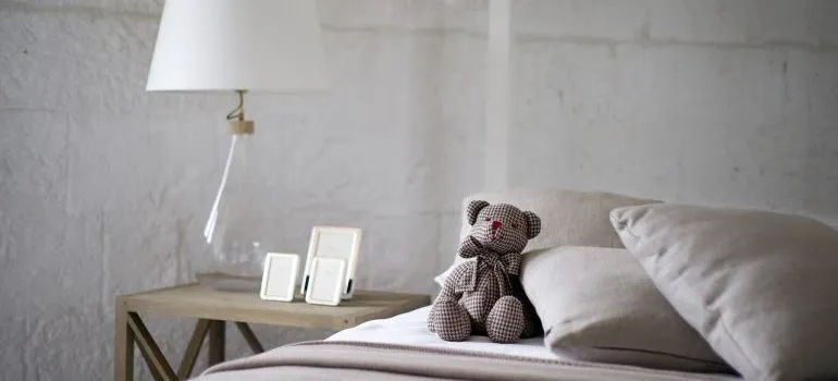 A grey bed with a teddy bear on it.