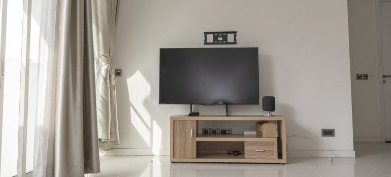 A plasma TV on a TV stand before packing the living room.