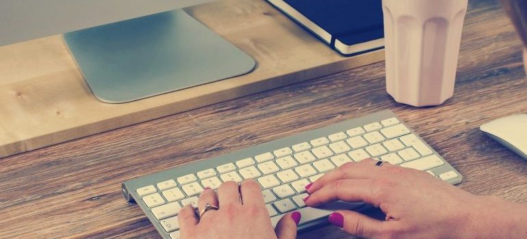 A woman typing on a keyboard, interested in getting an accurate moving estimate.