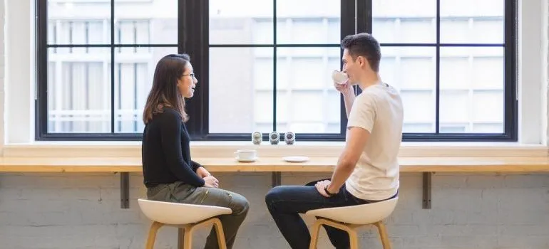 A man and a woman talking in a coffee shop.