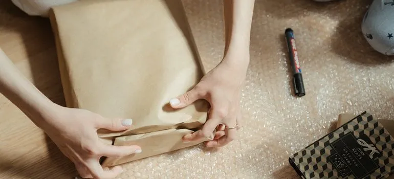 Person using a box and bubble wrap for moving cables and electronics.