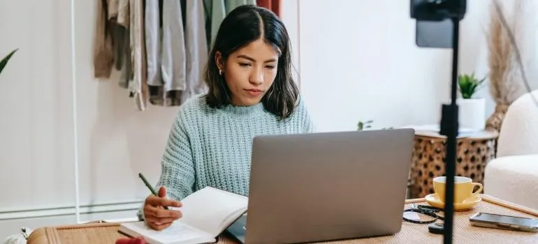 woman in front of the laptop, taking notes