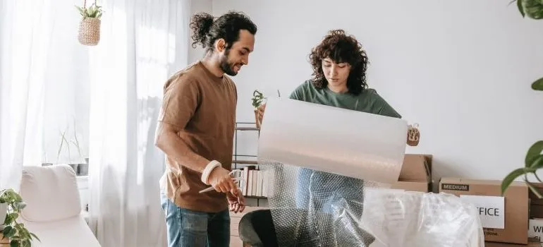 man and woman unrolling bubble wrapping