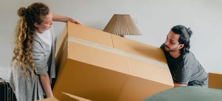 a couple lifting a large cardboard box