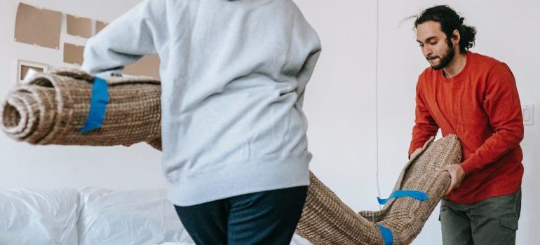 two people packing rugs and carpets for moving
