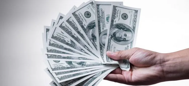 person holding a "fan" of $100 bills