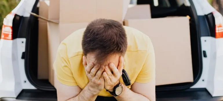 stressed man with moving boxes Coping with moving after divorce