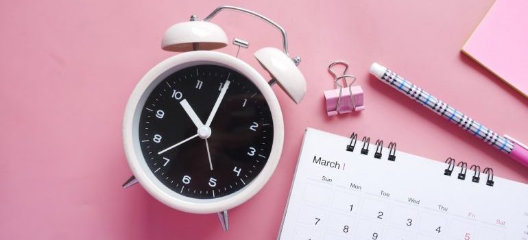 A clock and a calendar on a desk.