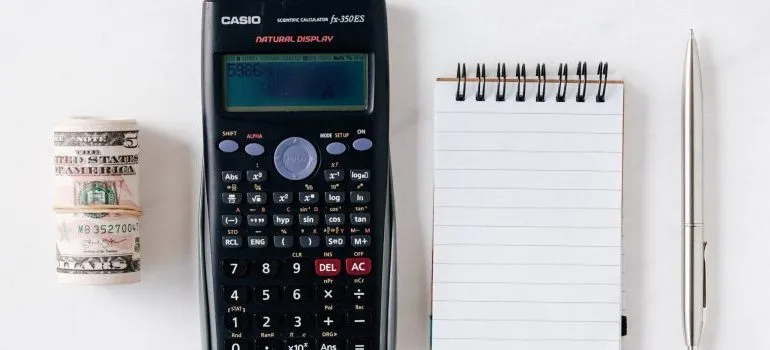 calculator, notepad, stack of $bills, representing what you need for moving from Seattle to Los Angeles