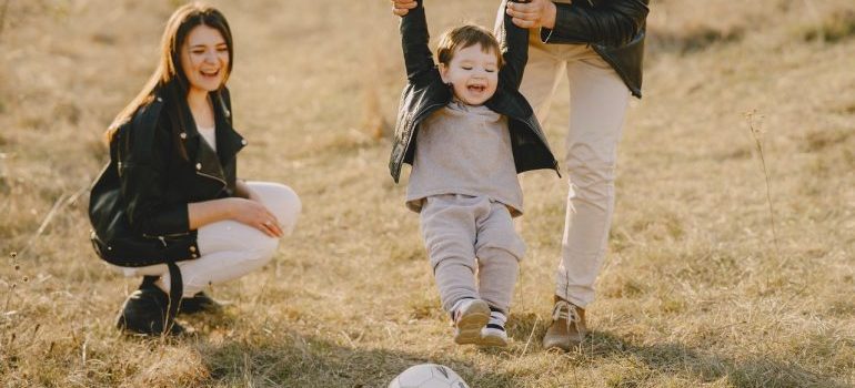 parents with their kid playing with a ball in the park is definitely one of the benefits of living in Newcastle WA