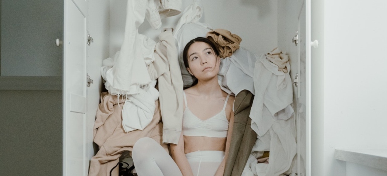 A woman overwhelmed with things in the closet.