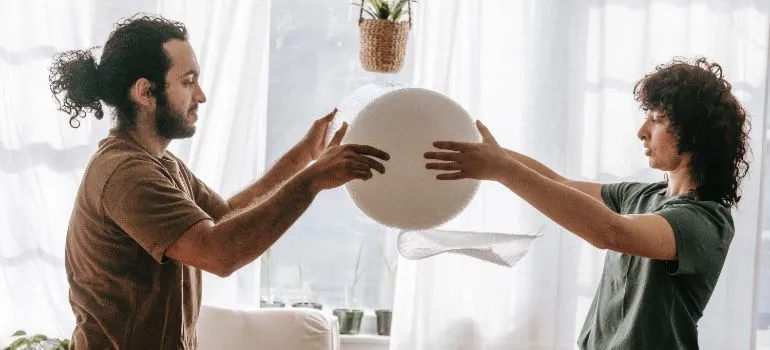 two people using bubble wrap for packing an armoire for transport