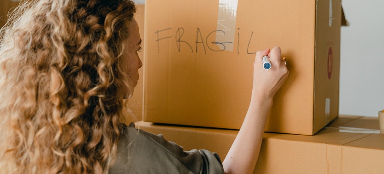 A woman labeling a moving box as she packs workshop for moving