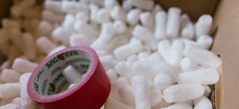 A packing tape in a box full of packing peanuts.