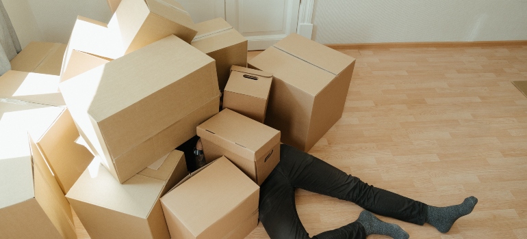 a person laying on the floor covered with boxes thinking of ways to cure moving exhaustion