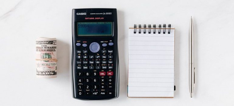 A calculator, notebook, and money bills