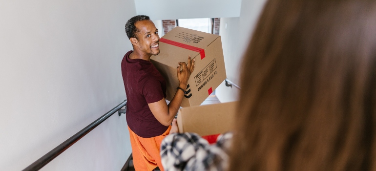 smiling man carrying moving box