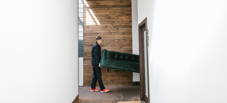 focused man carrying green sofa