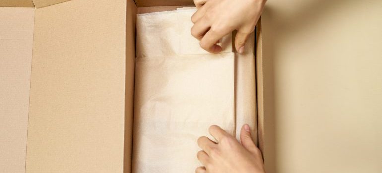 A person using packing paper and a box