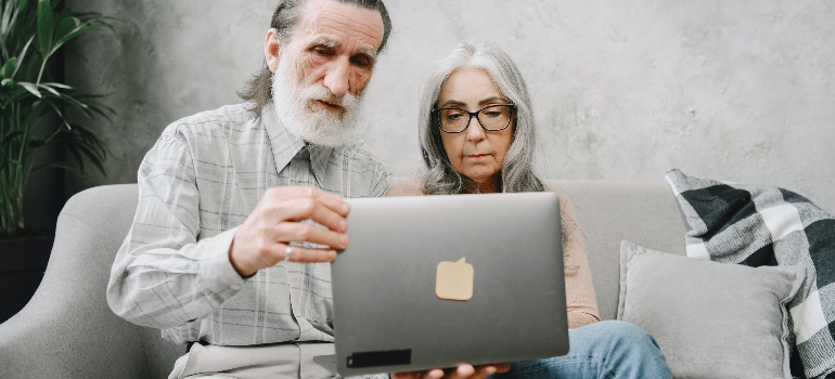 an elderly couple reading about planning your retirement relocation from Washington on their laptop