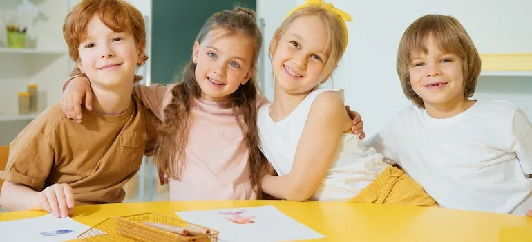 four young kids hugging in a classroom after moving from Kirkland to Redmond