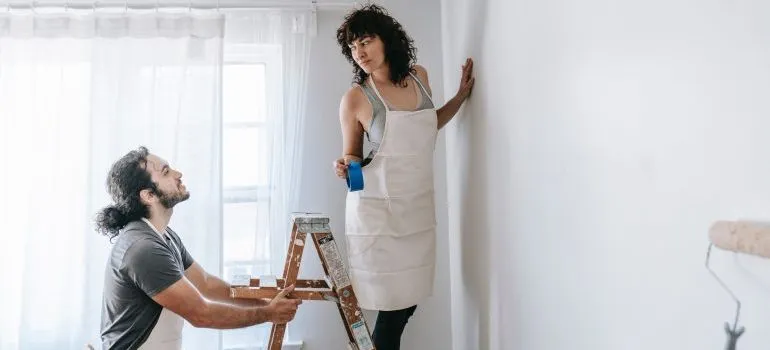 A couple painting walls while talking about why West Seattle is ideal for young adults