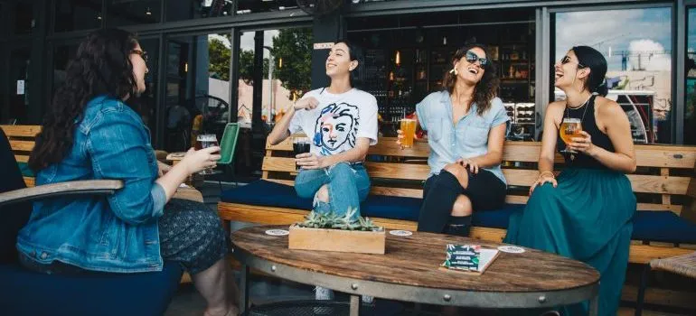 Women in a pub having drinks and discussing why West Seattle is ideal for young adults