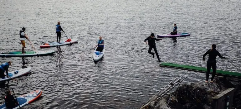 People paddleboarding and jumping in the water