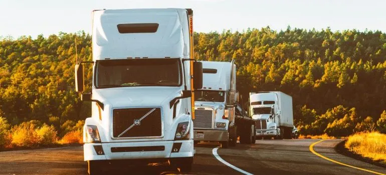 Three large trucks on the road during the heavy equipment transport process