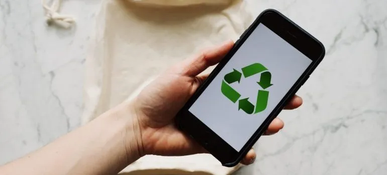 Person holding a phone with the recycling logo