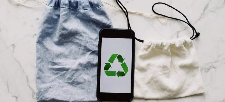 Two bags and a phone with recycling logo