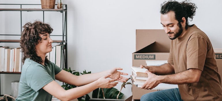 A Couple Packing Books In A Box