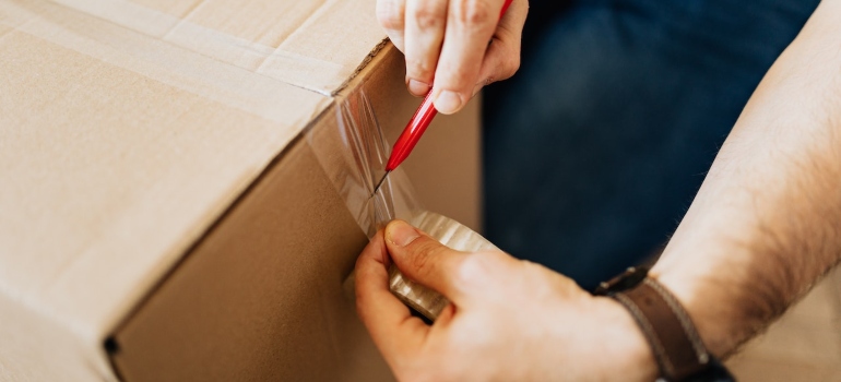 One of the movers North Bend WA is sealing carton box for moving out