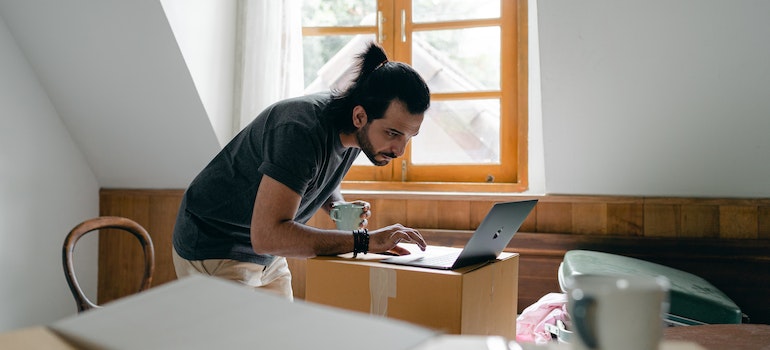 Man using laptop on carton box