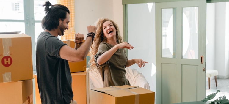 Happy couple unpacking boxes and dancing