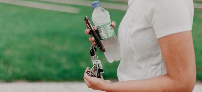 Person holding water, keys, and a phone