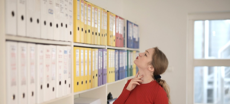 a woman looking at cardboard folders thinking about decluttering your Seattle office