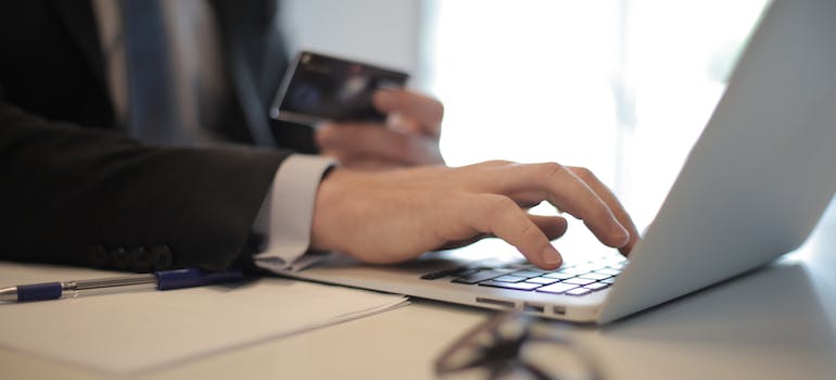 A person in a black suit typing on a computer