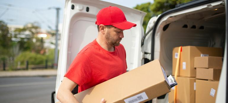 A Man in Red Shirt Carrying a Cardboard Box Beside the Van providing cross-dock solutions