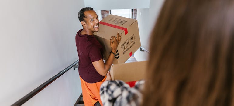 A man going down the stairs while carrying a box