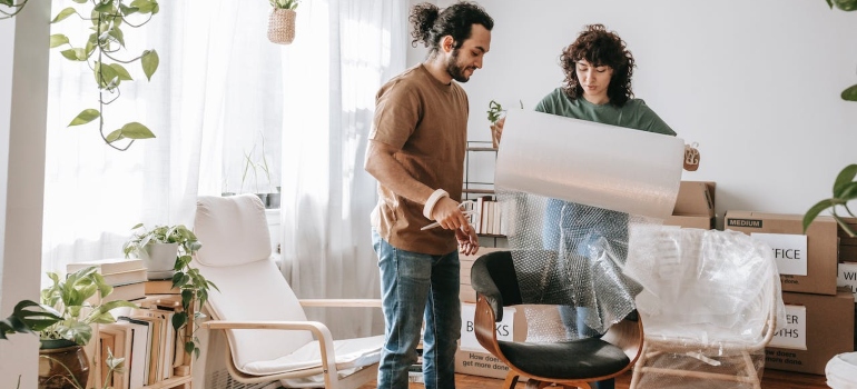 Couple wrapping a chair with bubble wrap using effective packing strategies