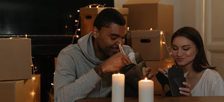 A couple eating take out amid boxes and festive lights