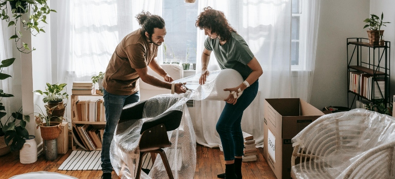 Couple Putting Bubble Wrap On Chairs
