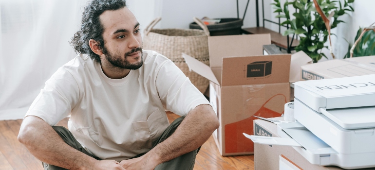 Man Sitting On Floor Beside Boxes is printing lables